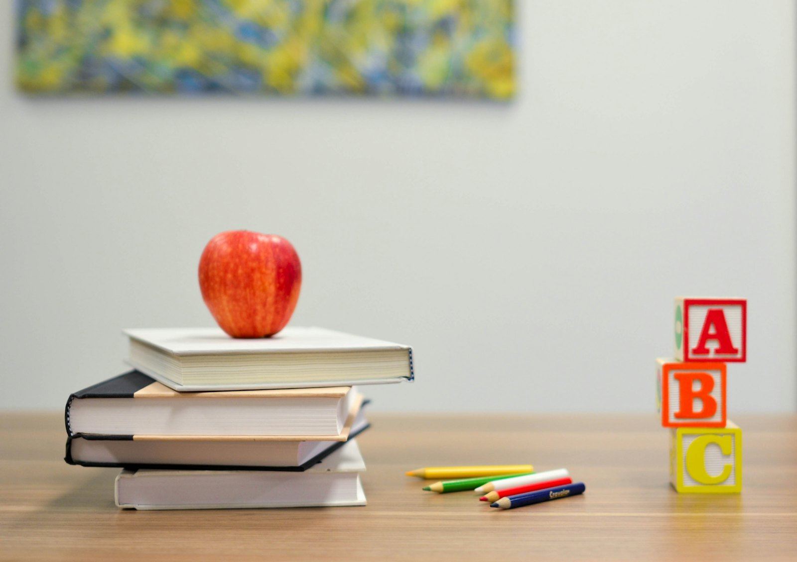 Books, an apple and alphabet blocks on a classroom table